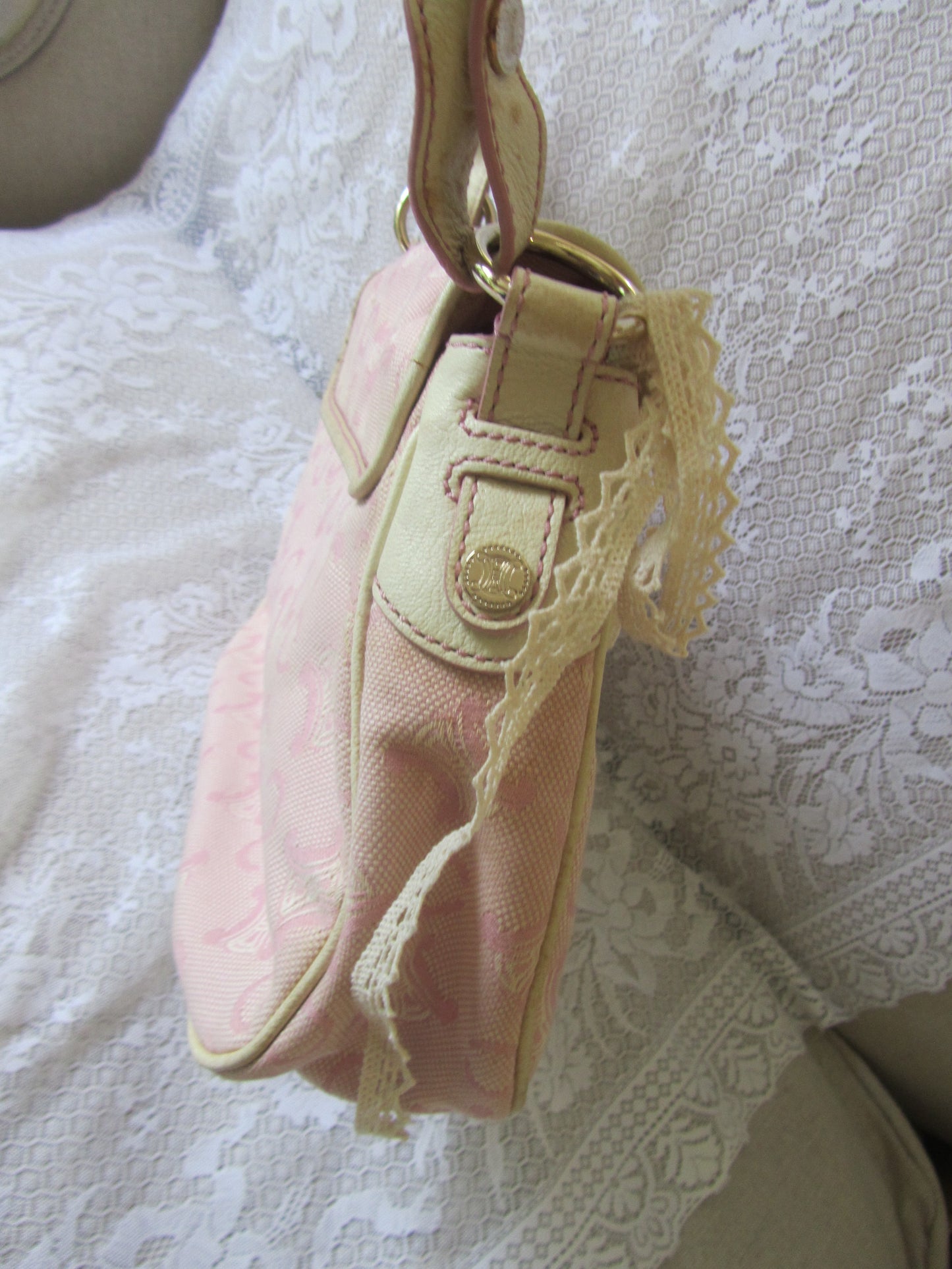 Pink handbag with lace detailing on a textured surface