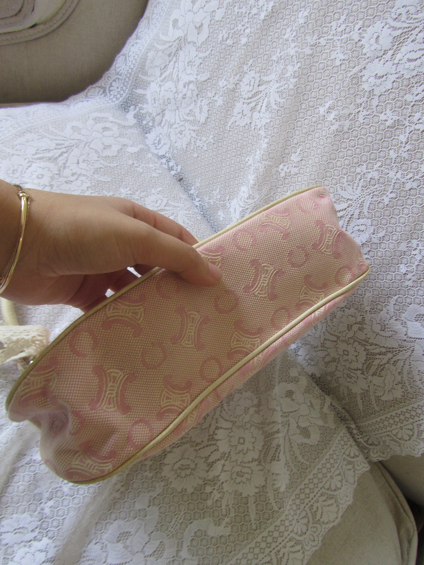 Hand holding a pink wallet with a brand logo against a textured white background