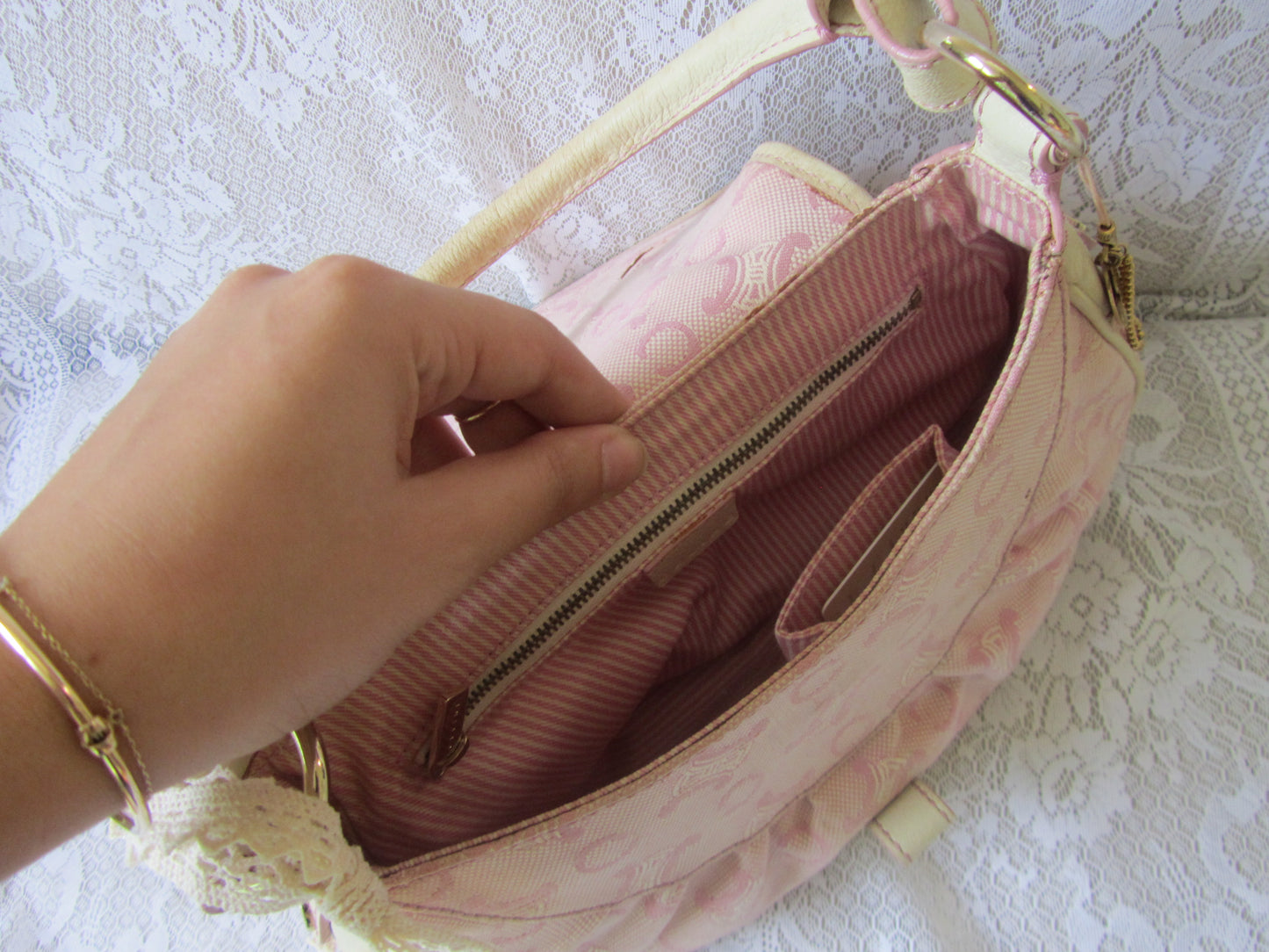 Pink handbag with a hand opening it on a textured white background