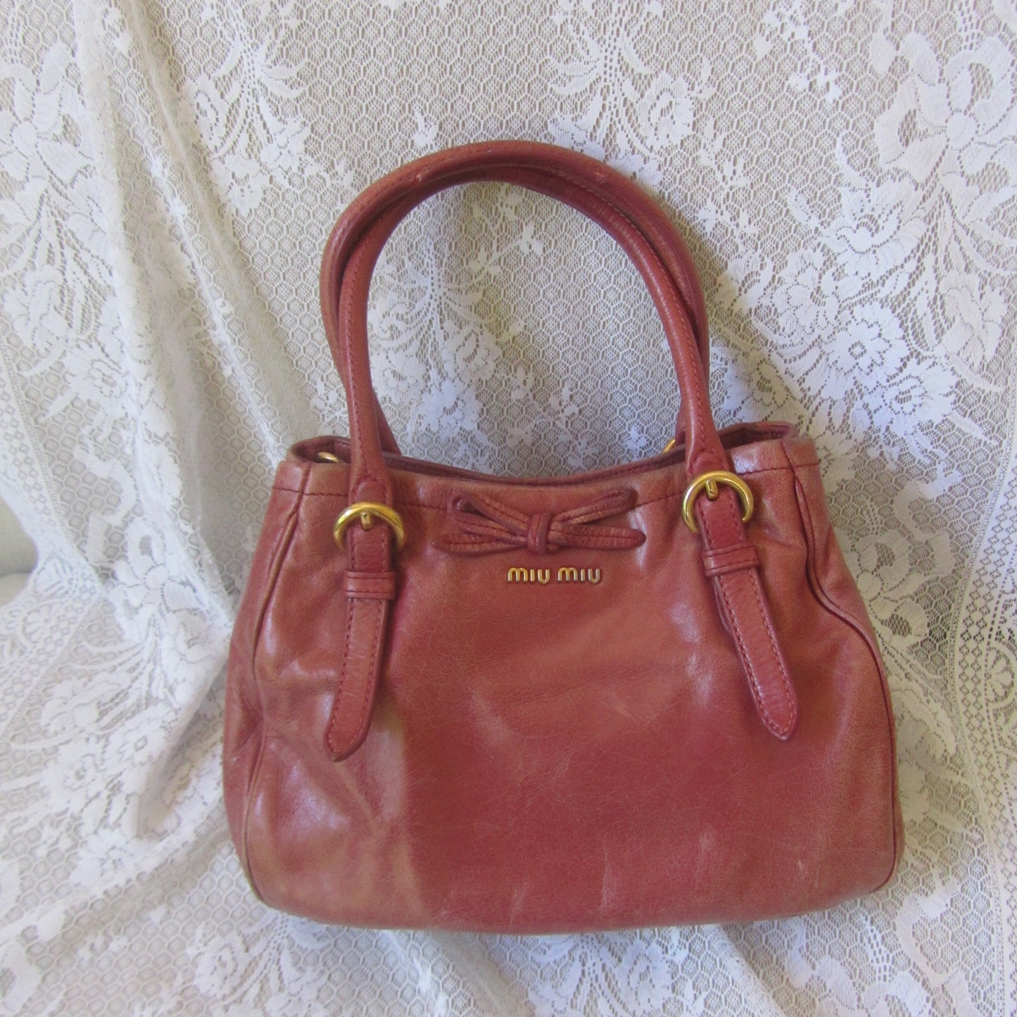 pink leather handbag on a textured beige surface