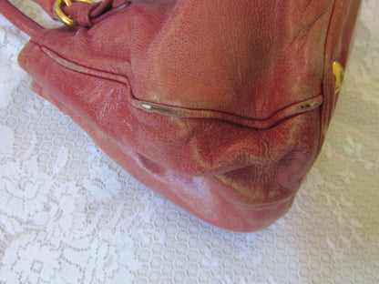 Close-up of a red leather handbag on a textured white surface