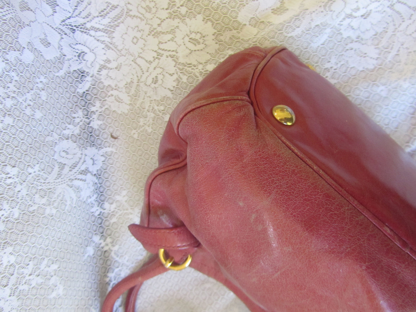 Red handbag with gold accents on a textured white surface