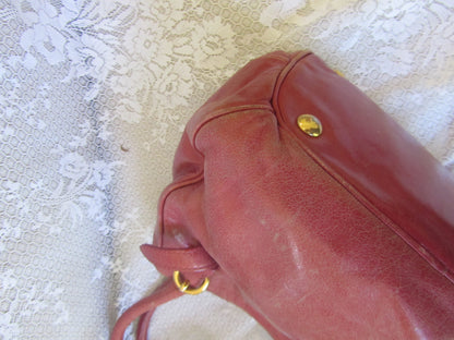 Red handbag with gold accents on a textured white surface