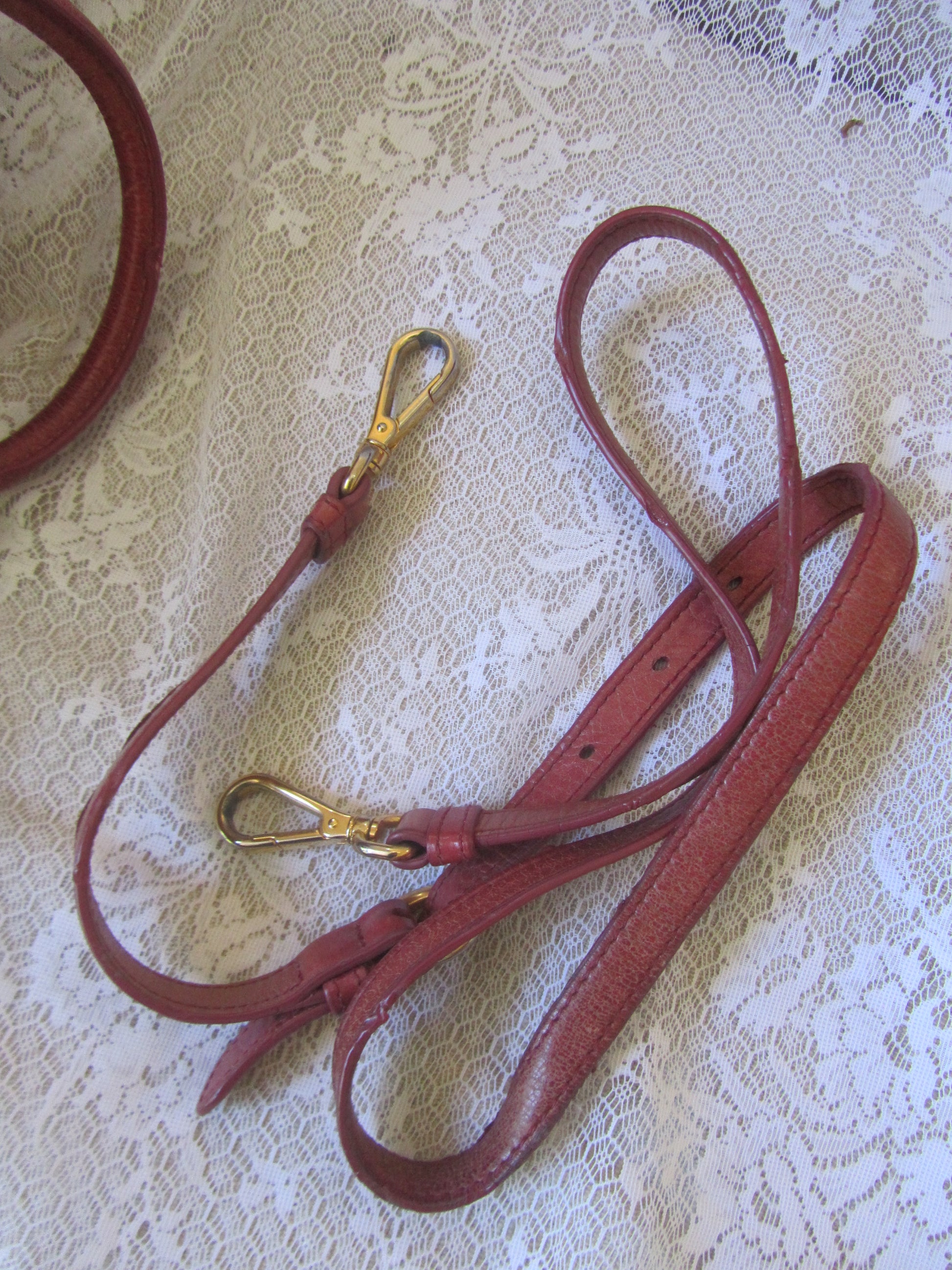 Red leather strap with gold clasp on a textured white background