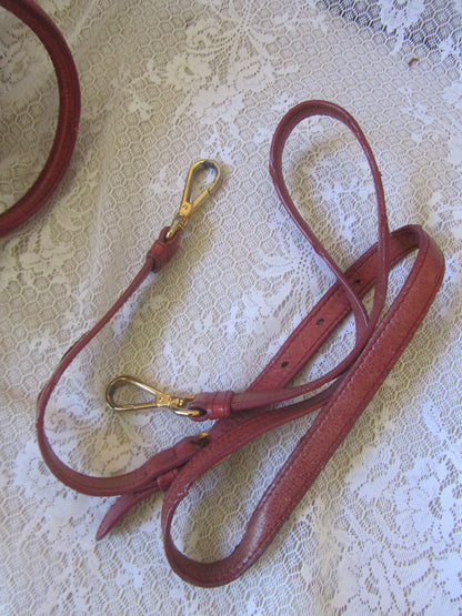 Red leather strap with gold clasp on a textured white background