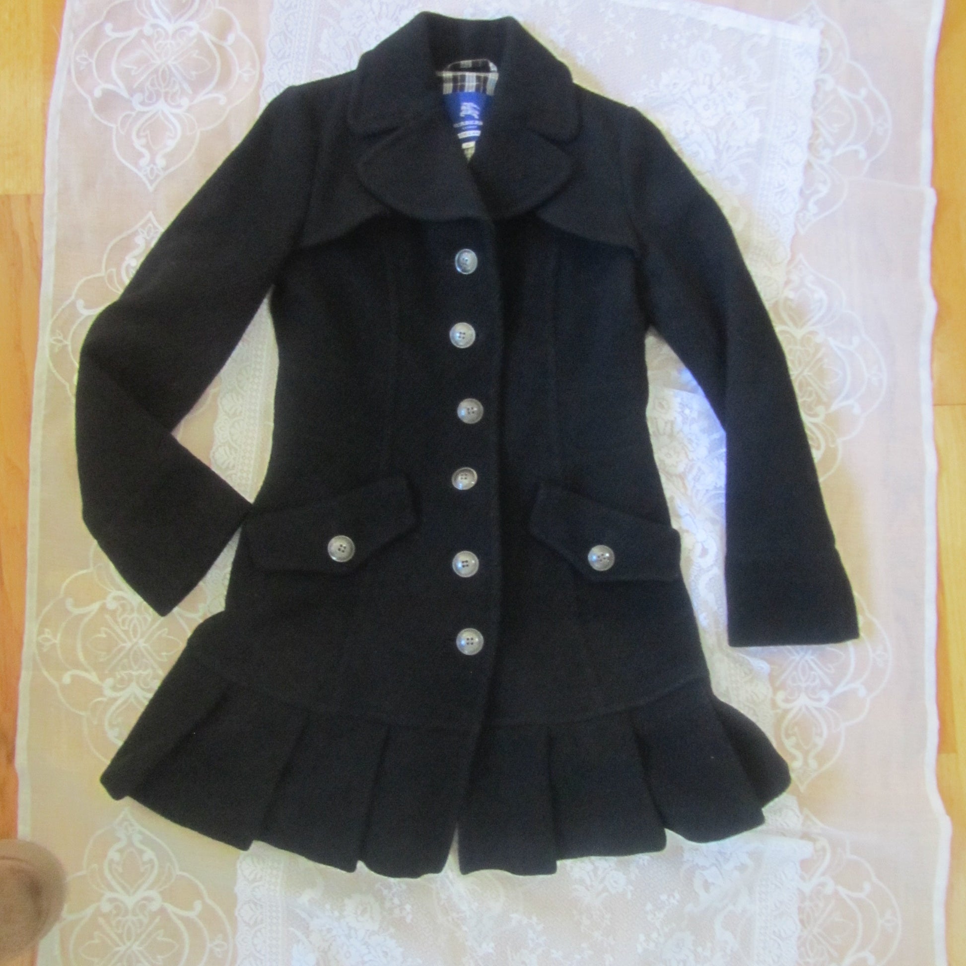 Black coat with white buttons on a lace tablecloth