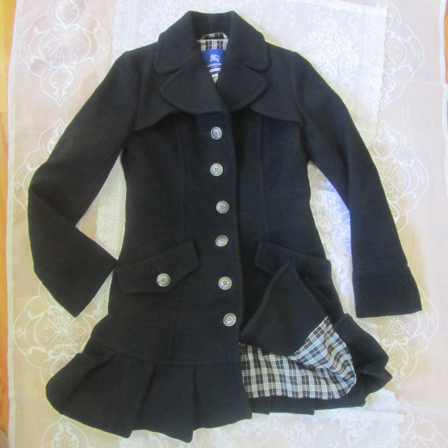 Black coat with plaid lining on a white surface