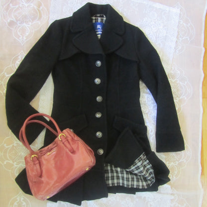 Black coat with plaid lining and pink handbag on a white lace tablecloth