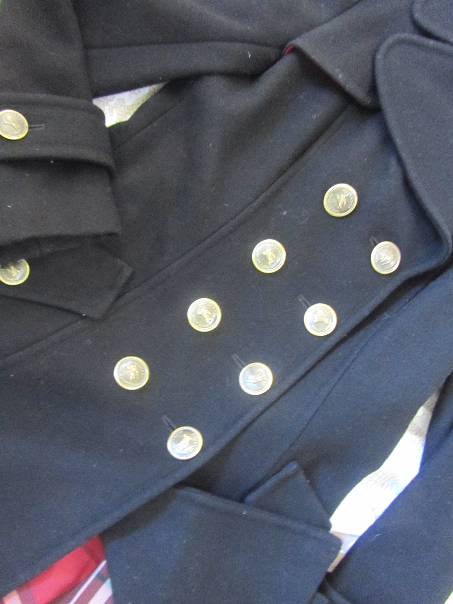 Close-up of a navy blue coat with gold buttons on a white background