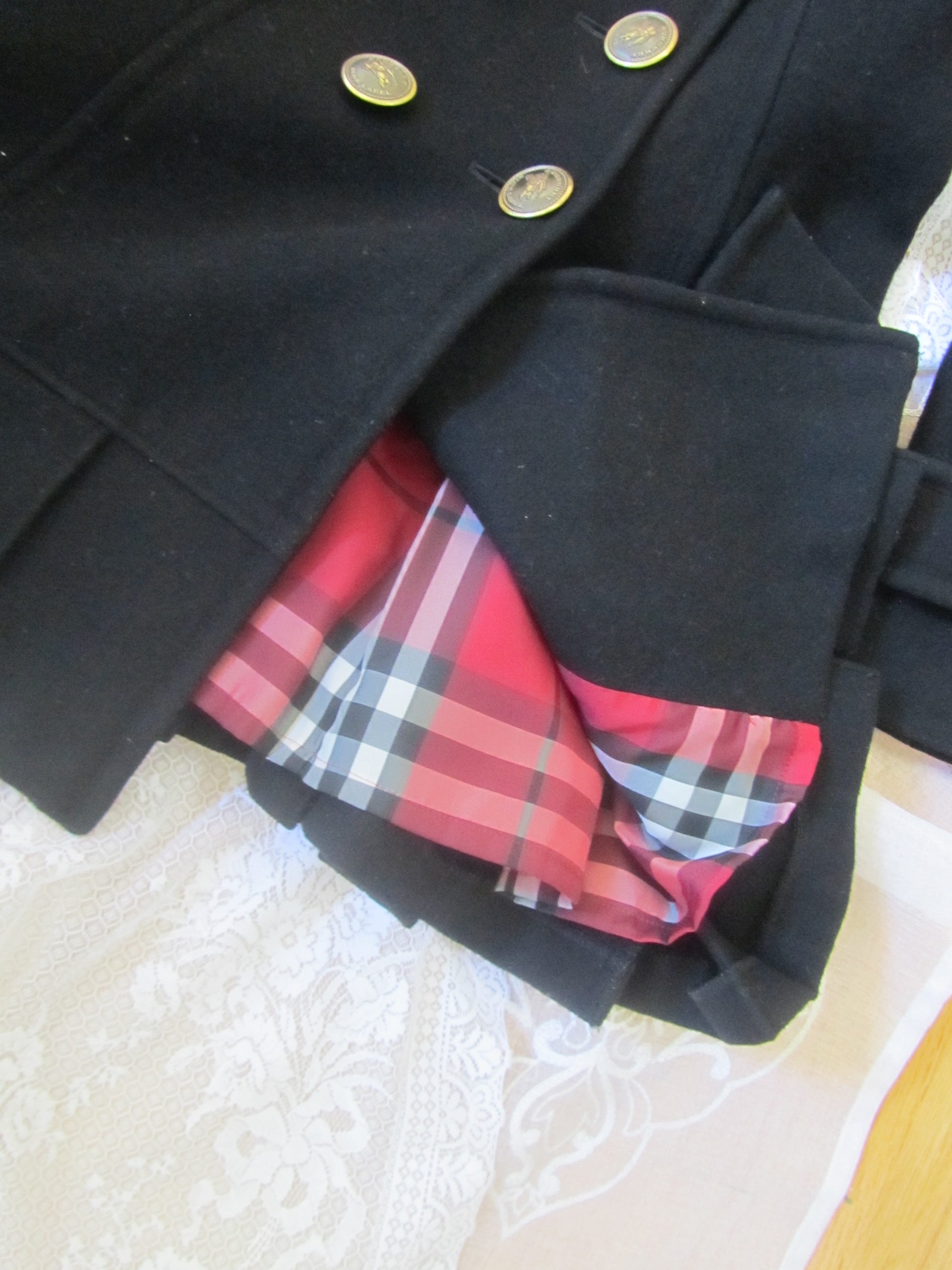 Black coat with plaid lining on a white surface