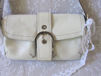 White handbag with a decorative strap on a lace background
