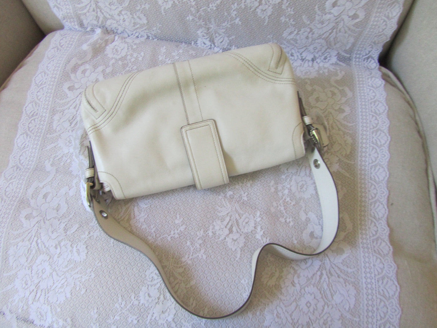 White leather handbag with a strap on a textured surface