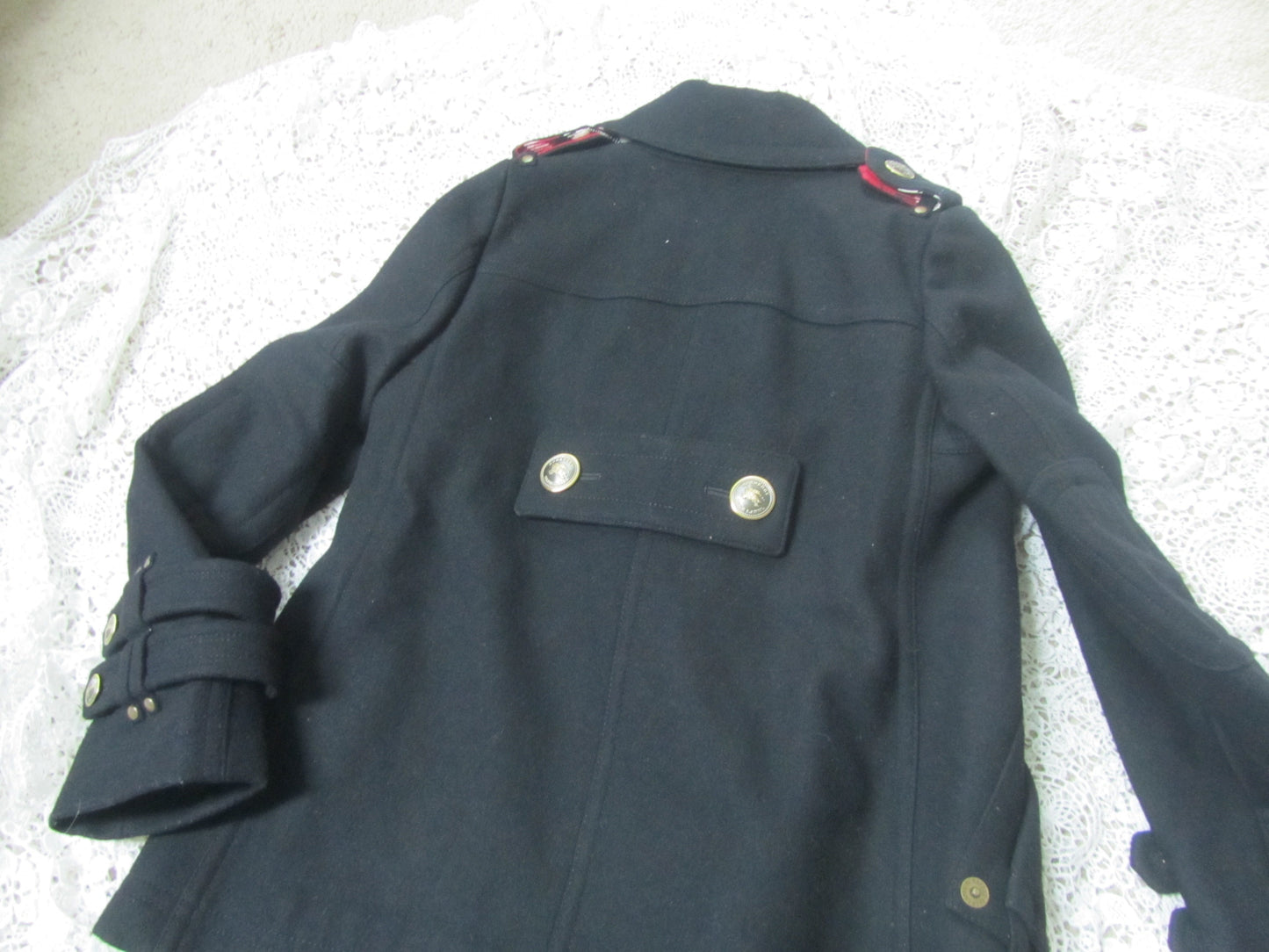 black peacoat and golden buttons on a lace background