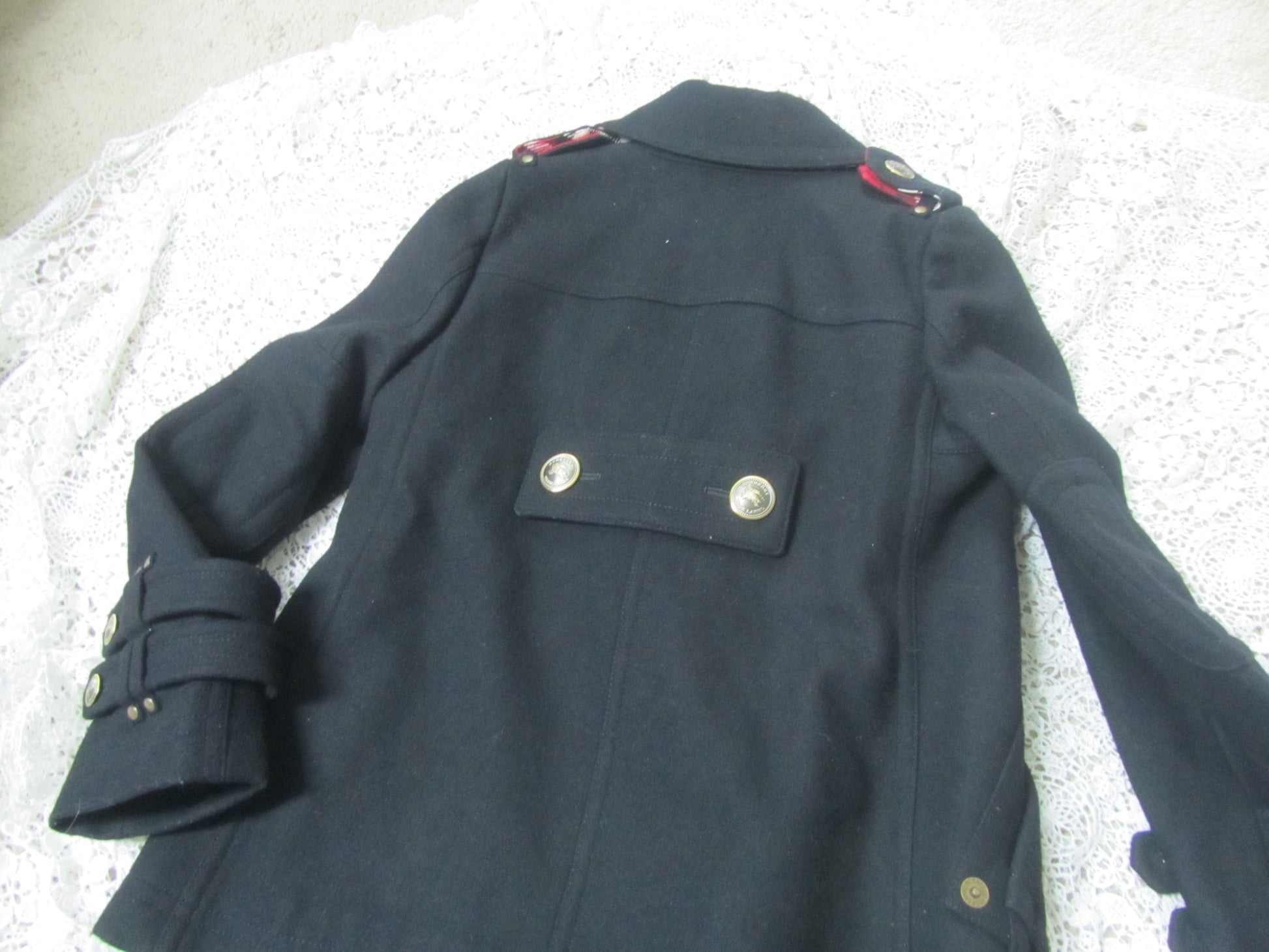 black peacoat and golden buttons on a lace background