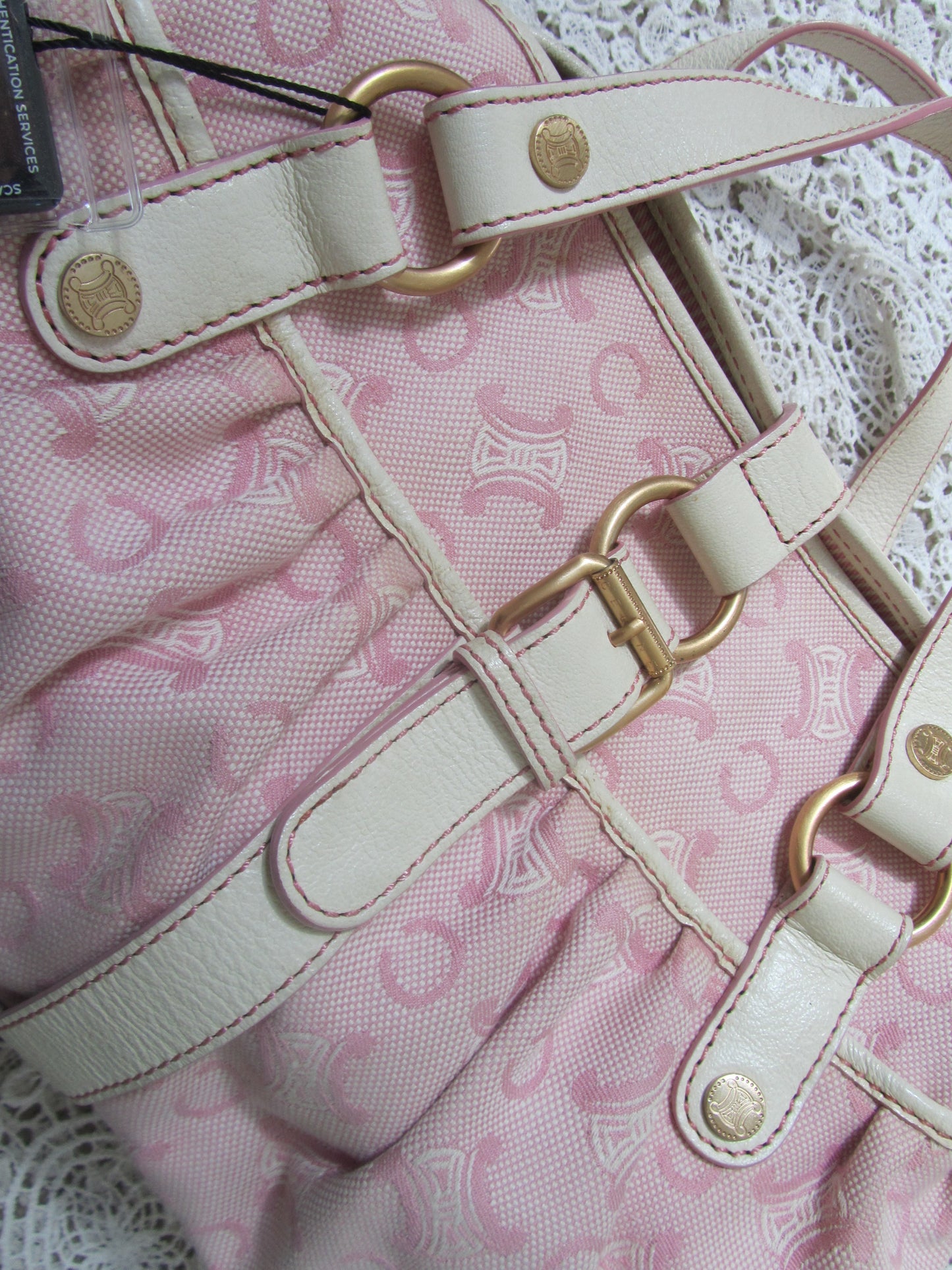 pink celine bag with cream handles and gold details on a lace background  