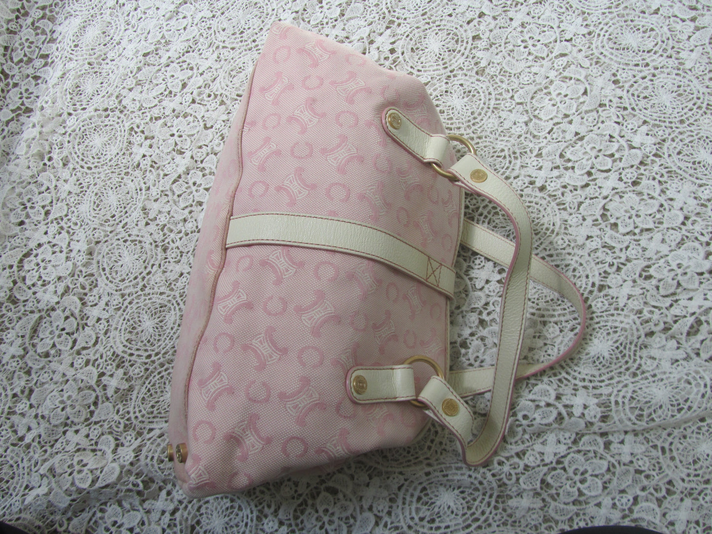 pink celine bag with cream handles and gold details on a lace background  