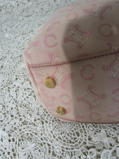 the corner of a pink celine bag with  gold details on a lace background  