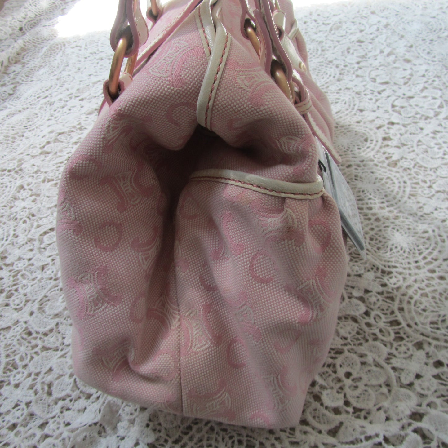 pink celine bag with cream handles and gold details on a lace background  