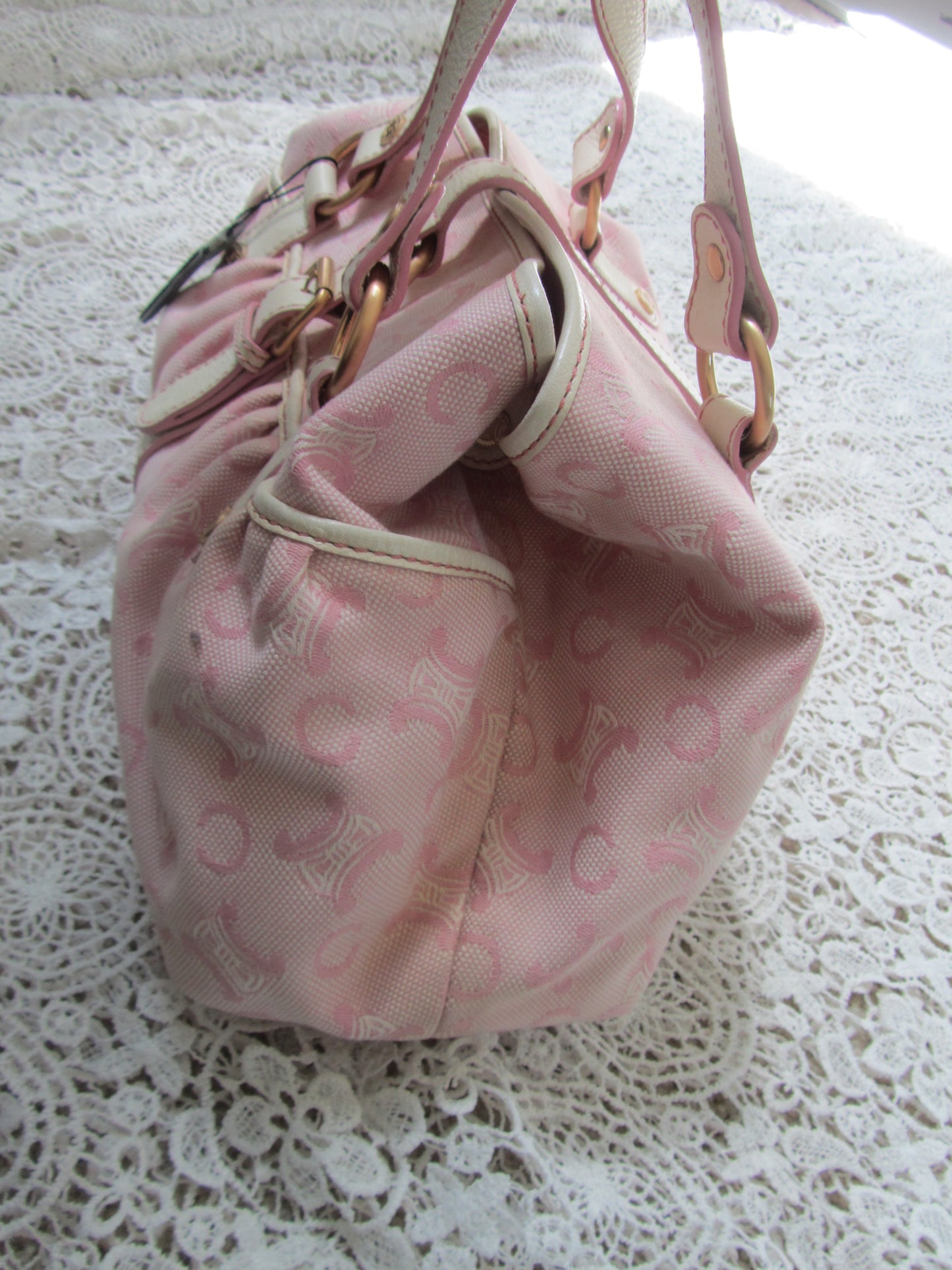 pink celine bag with cream handles and gold details on a lace background  