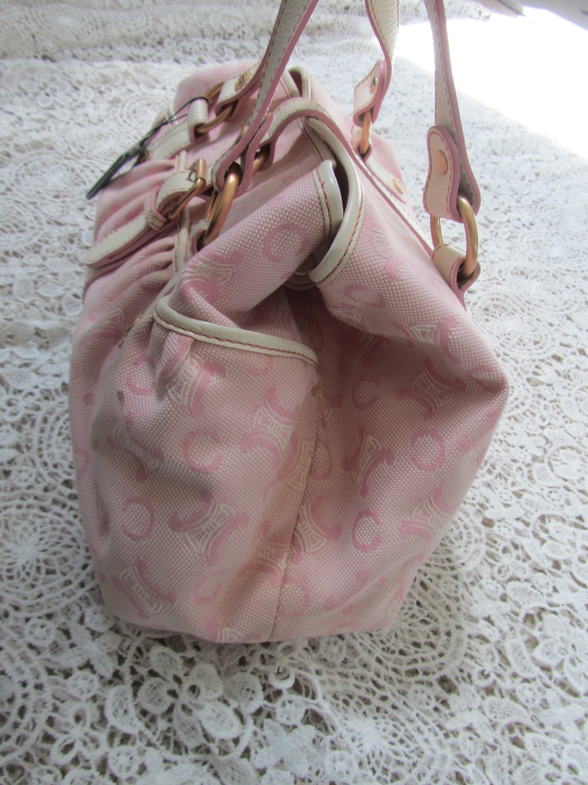 pink celine bag with cream handles and gold details on a lace background  