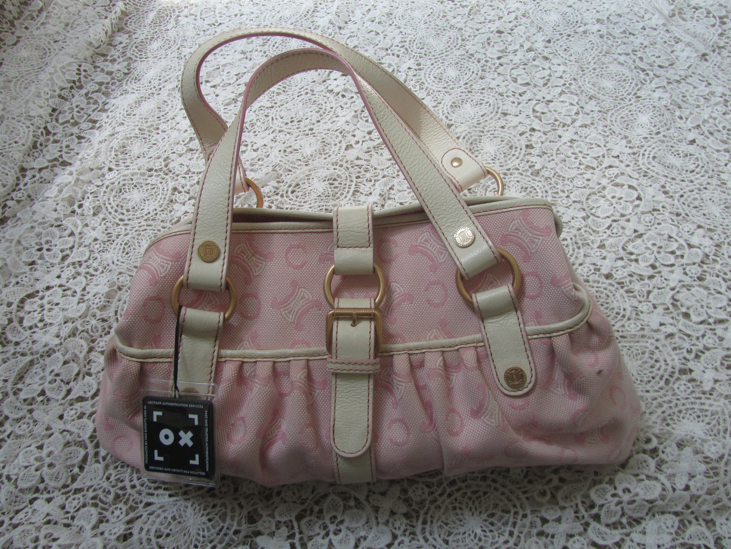 pink celine bag with cream handles and gold details on a lace background  