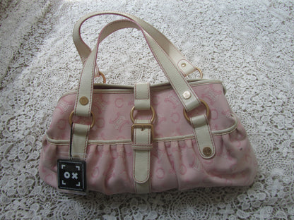 pink celine bag with cream handles and gold details on a lace background  