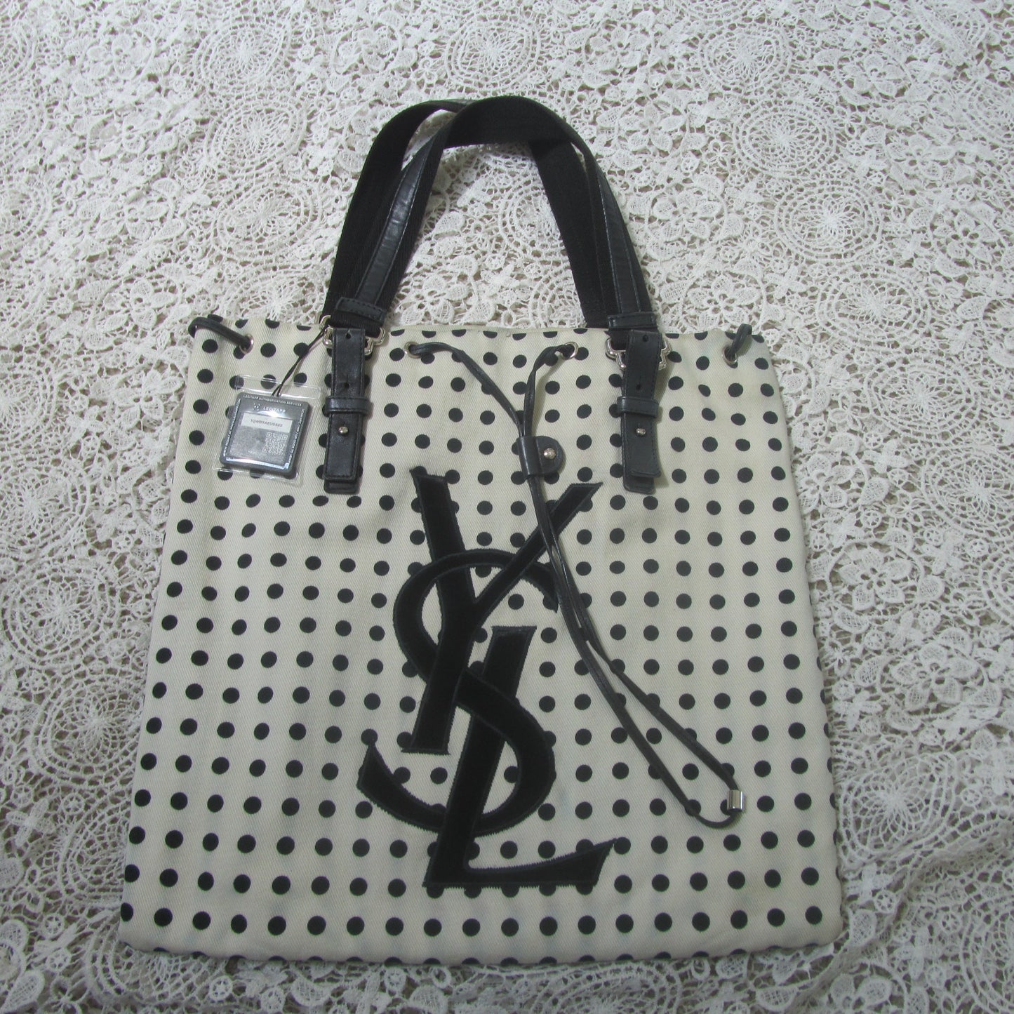 polkadot tote bag with YSL logo on a lace background 