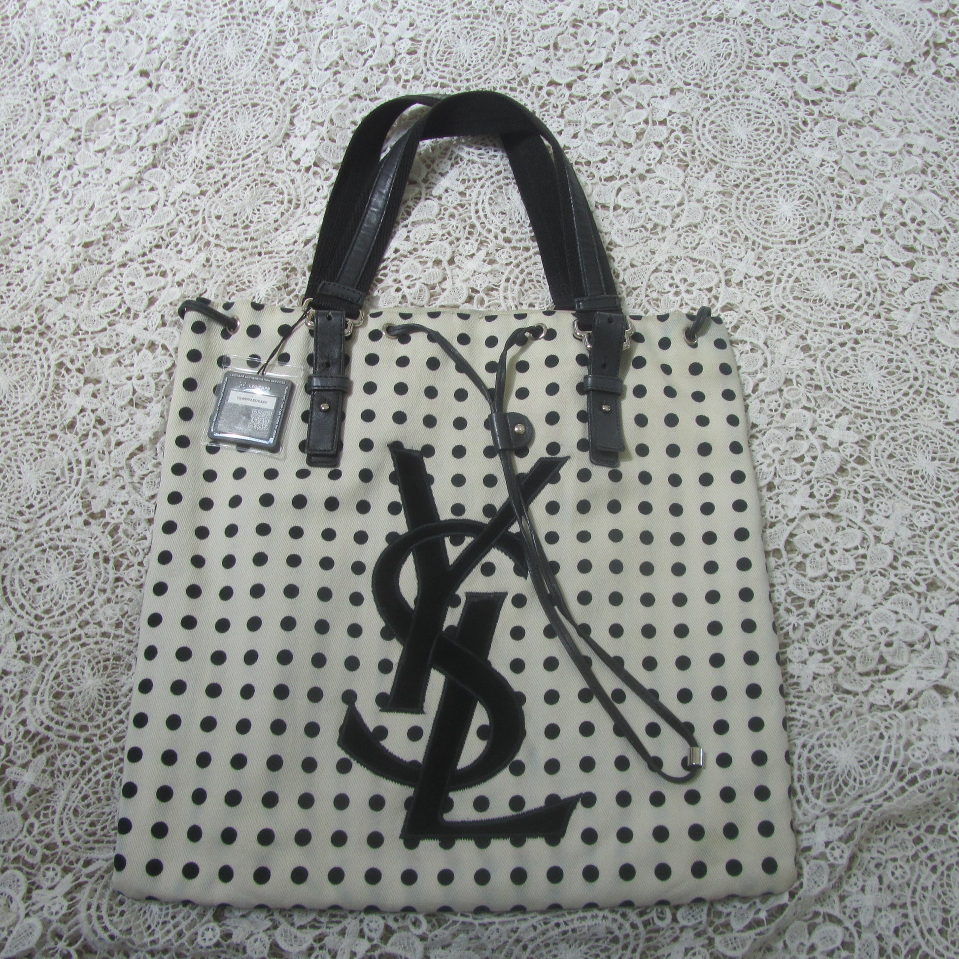 polkadot tote bag with YSL logo on a lace background 