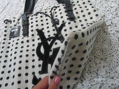 corner of a polkadot tote bag with YSL logo on a lace background 