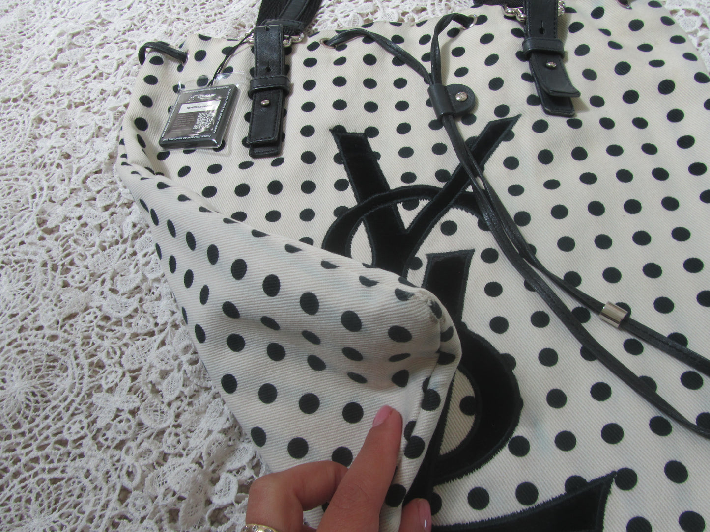 corner of a polkadot tote bag with YSL logo on a lace background 