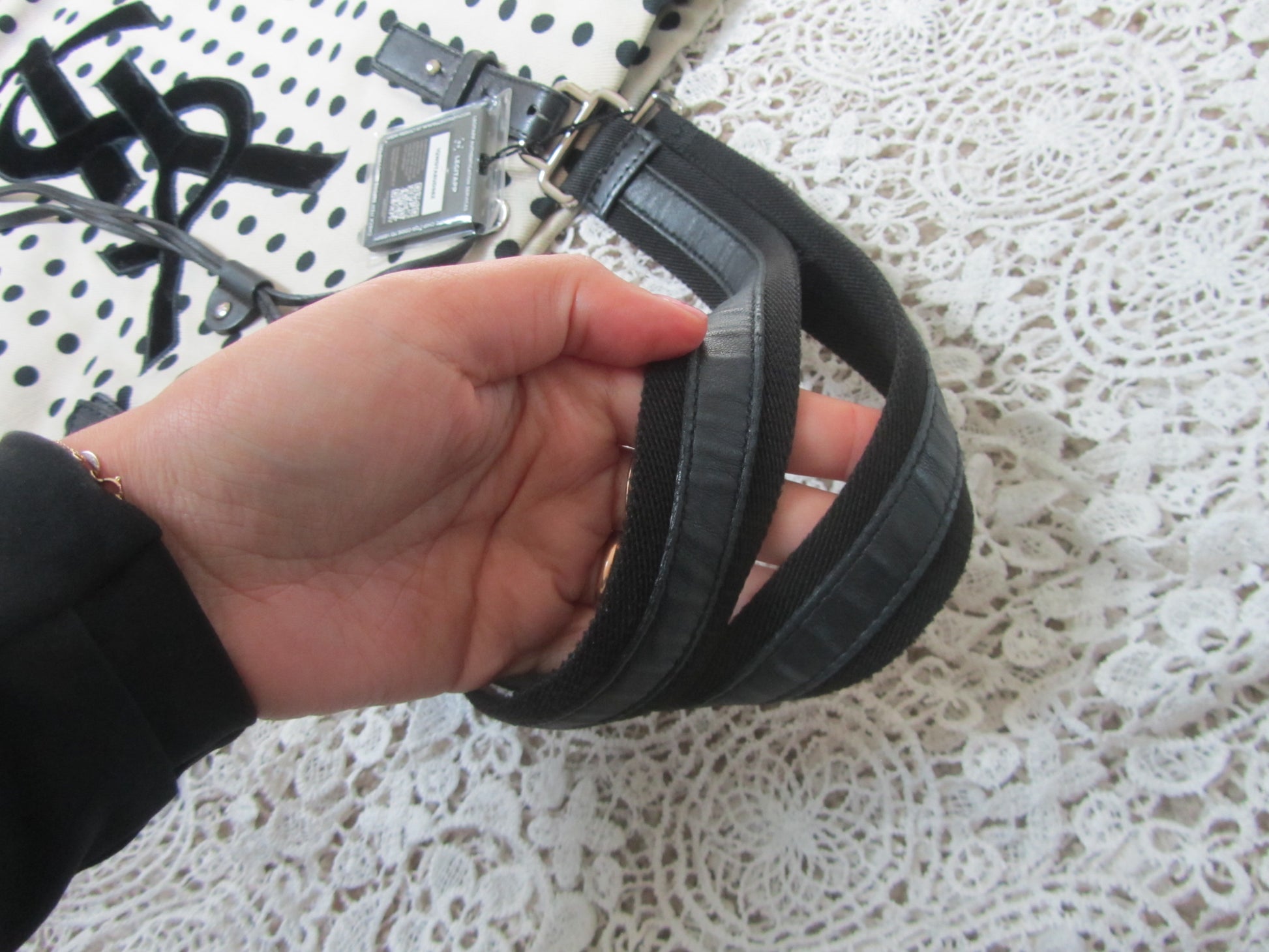 handles of a polkadot tote bag with YSL logo on a lace background 