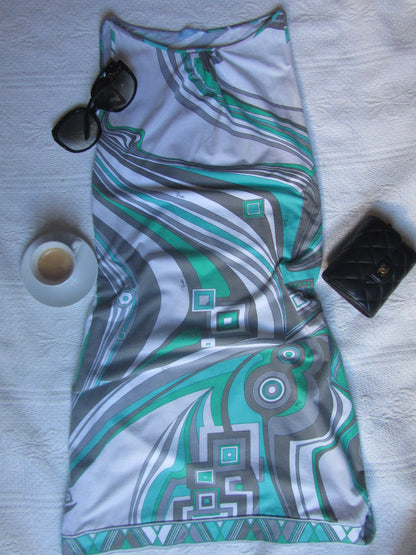 Patterned fabric with sunglasses and a small container on a textured surface