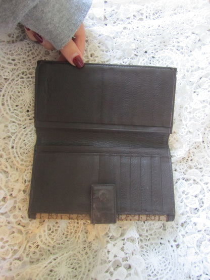 Brown leather wallet held by a hand on a textured white surface
