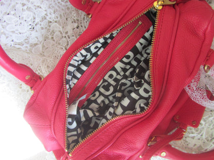 Red handbag with a black and white interior on a textured surface