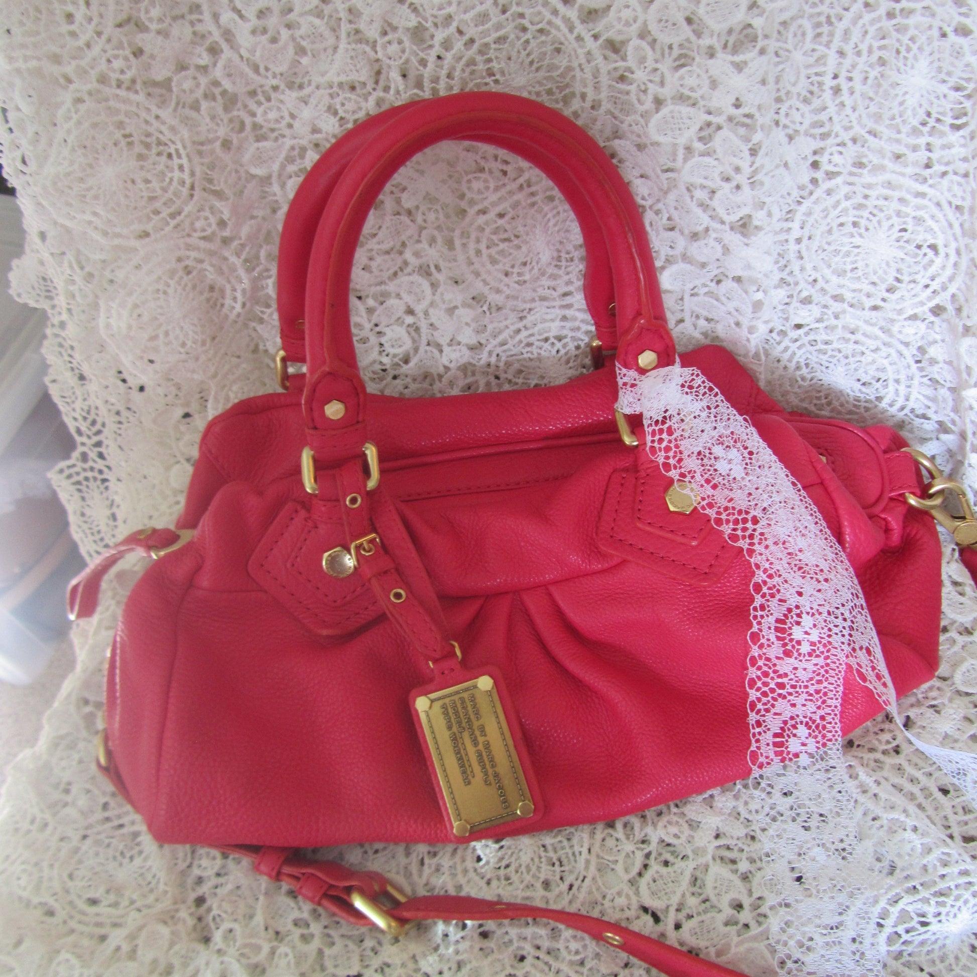 Red handbag with gold accents on a lace tablecloth