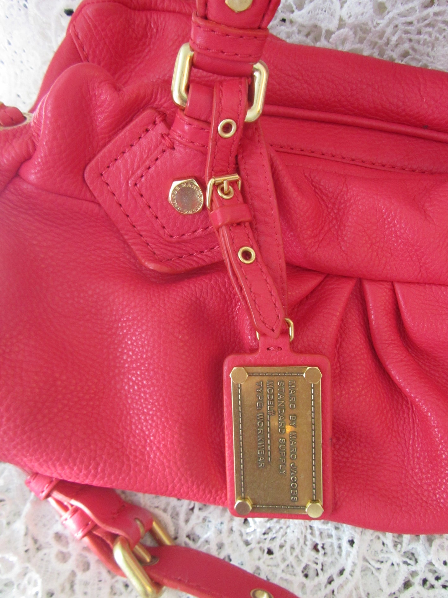 Red leather handbag with gold hardware on a textured surface