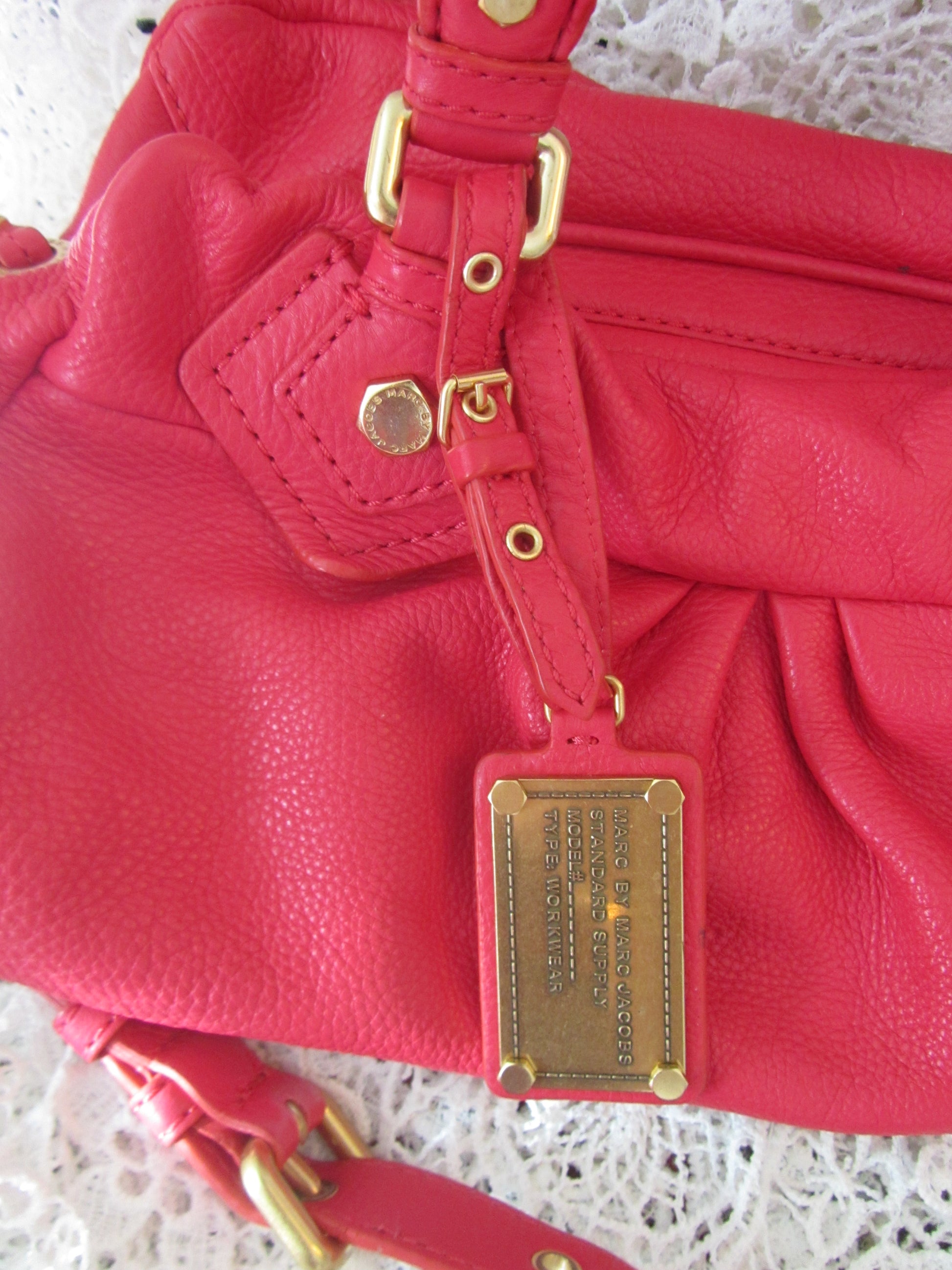 Red leather handbag with gold hardware on a textured surface