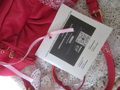 Red handbag with a certificate of authenticity on a lace surface