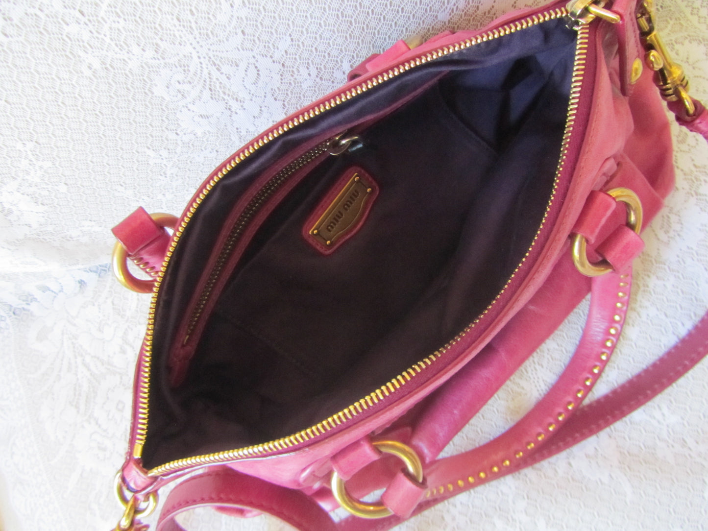 Pink handbag with gold accents on a textured white surface