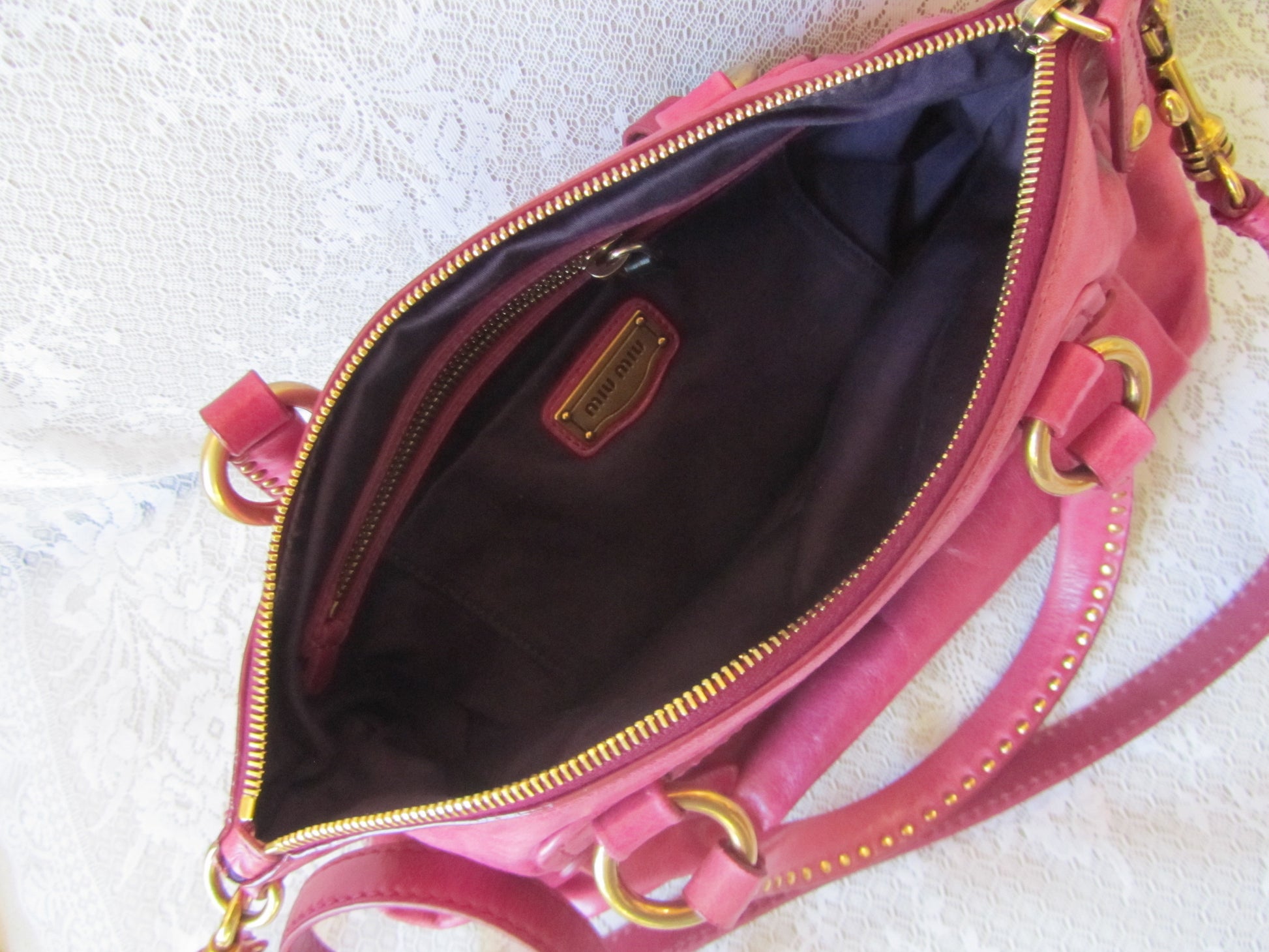 Pink handbag with gold accents on a textured white surface