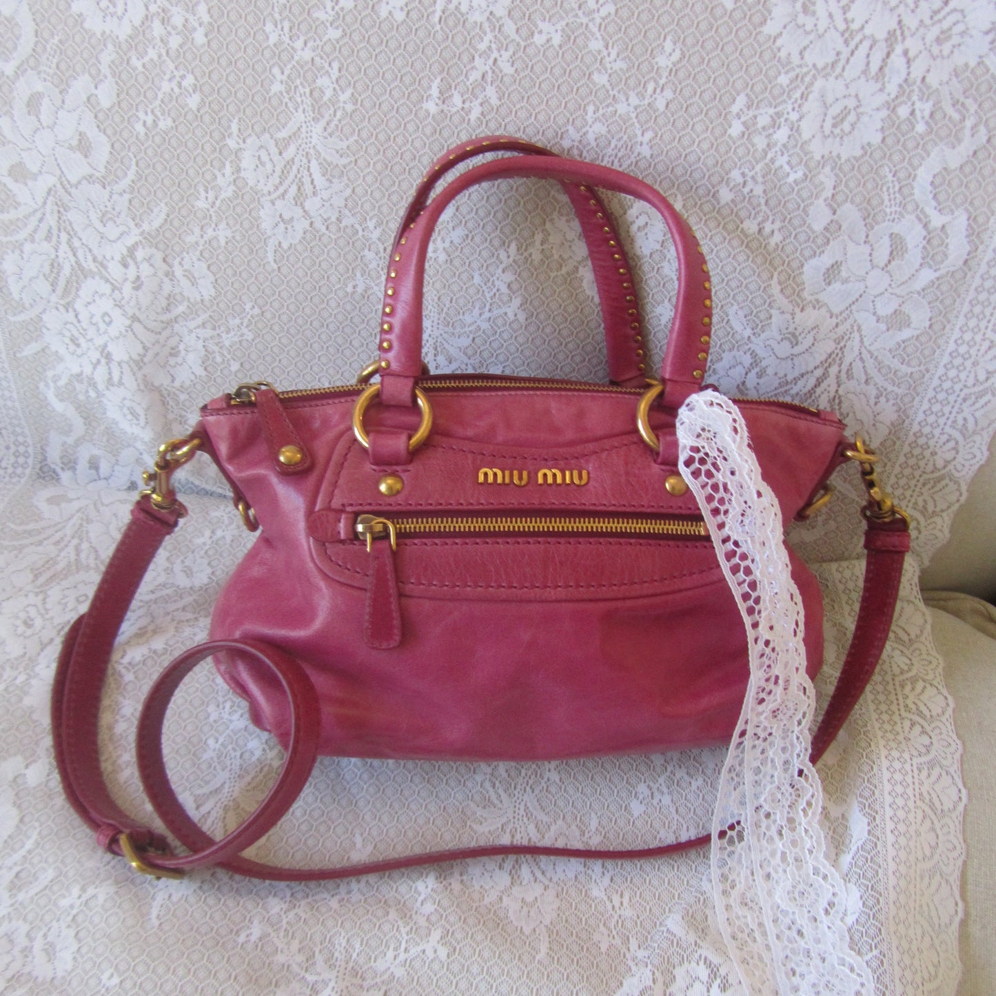 Pink handbag with gold accents on a textured white surface