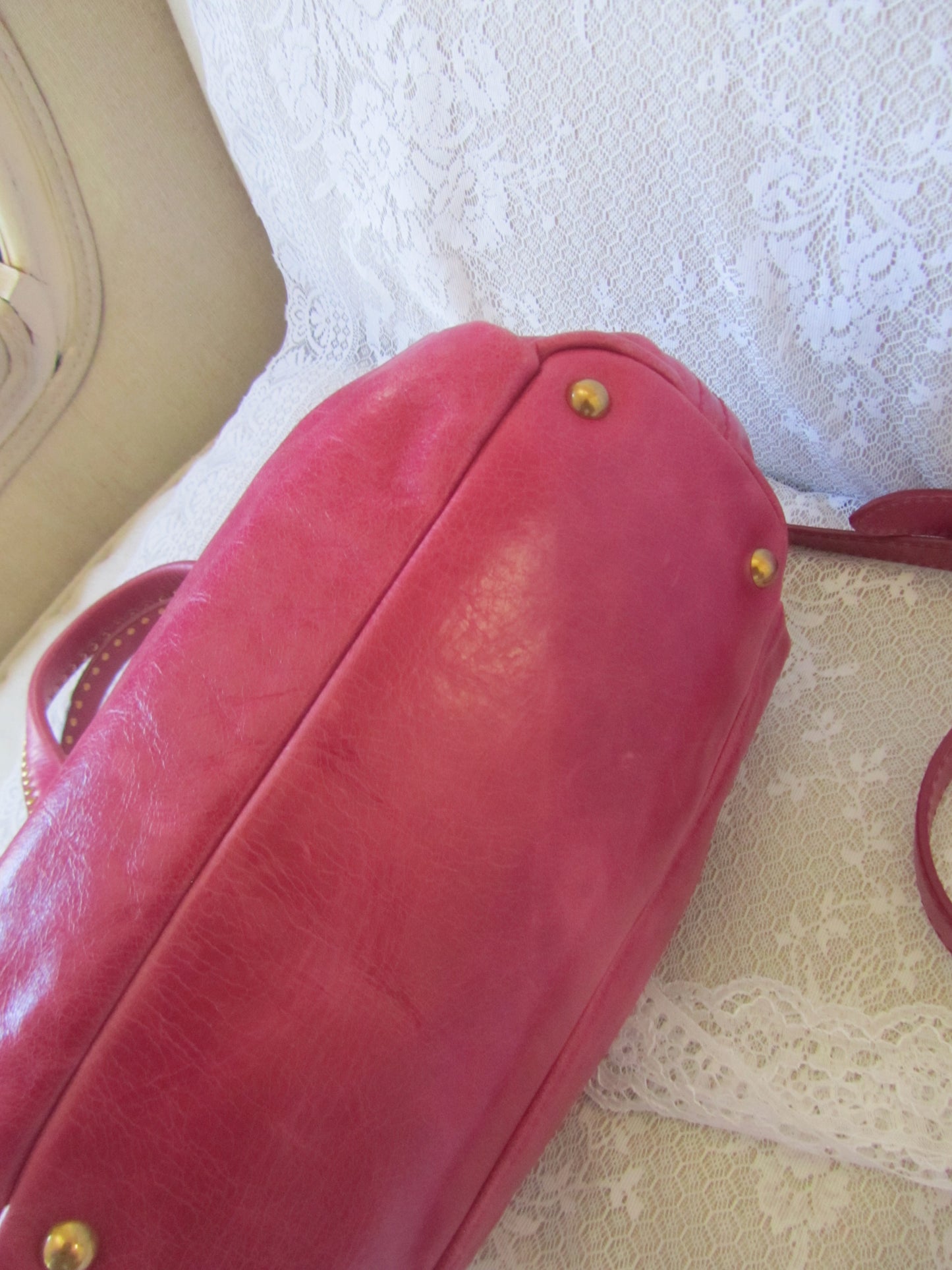 Red handbag with gold hardware on a textured white background
