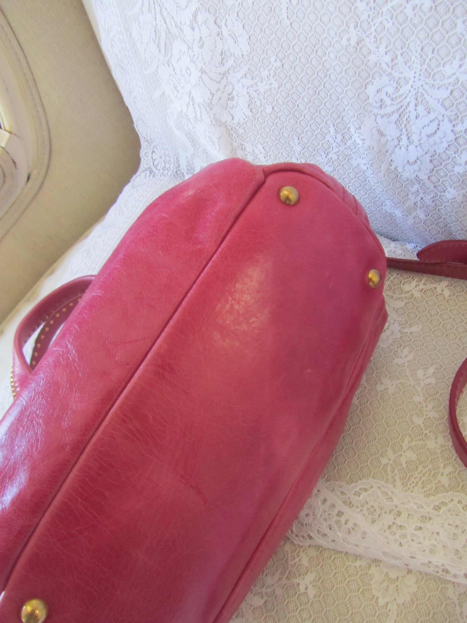 Red handbag with gold hardware on a textured white background