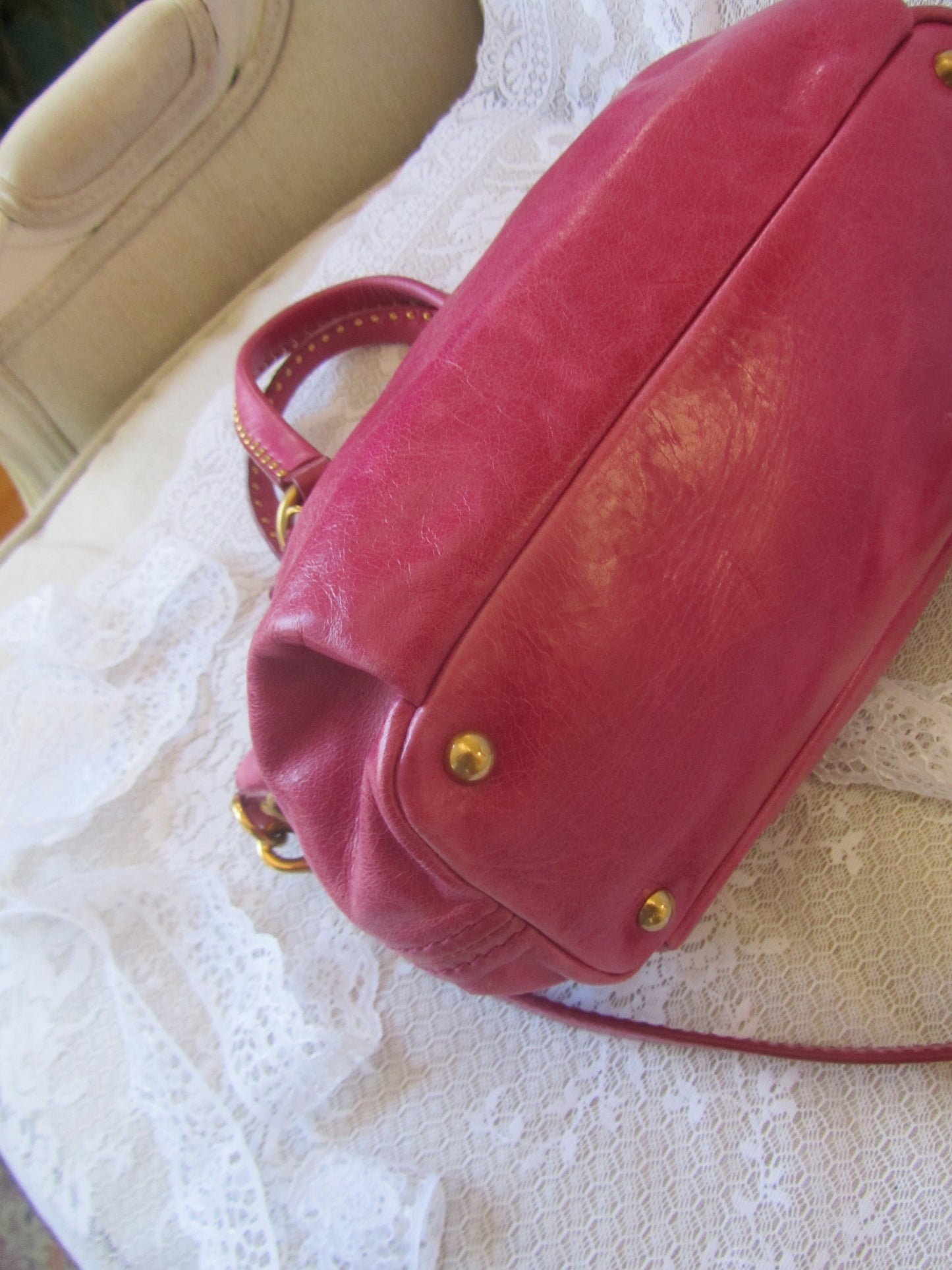 Red handbag with gold accents on a textured white surface