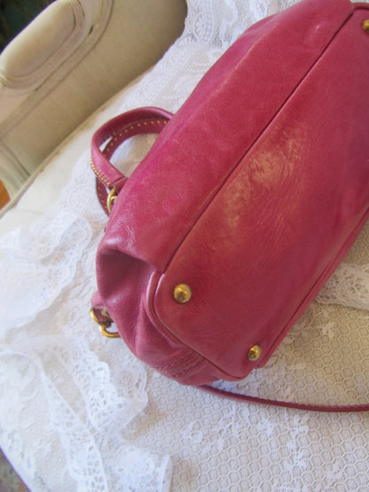 Red handbag with gold accents on a textured white surface
