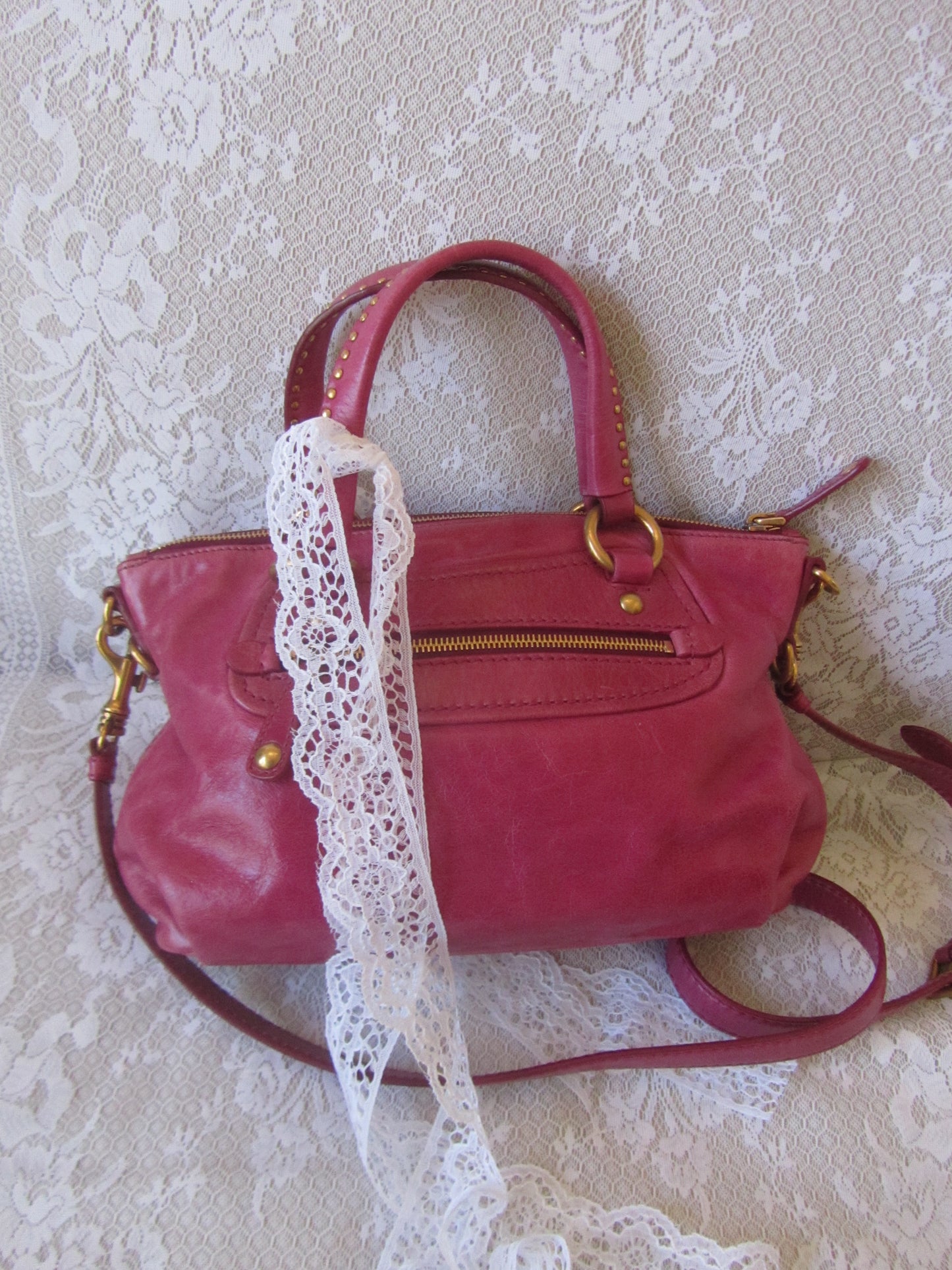 Red handbag with lace trim on a textured white background