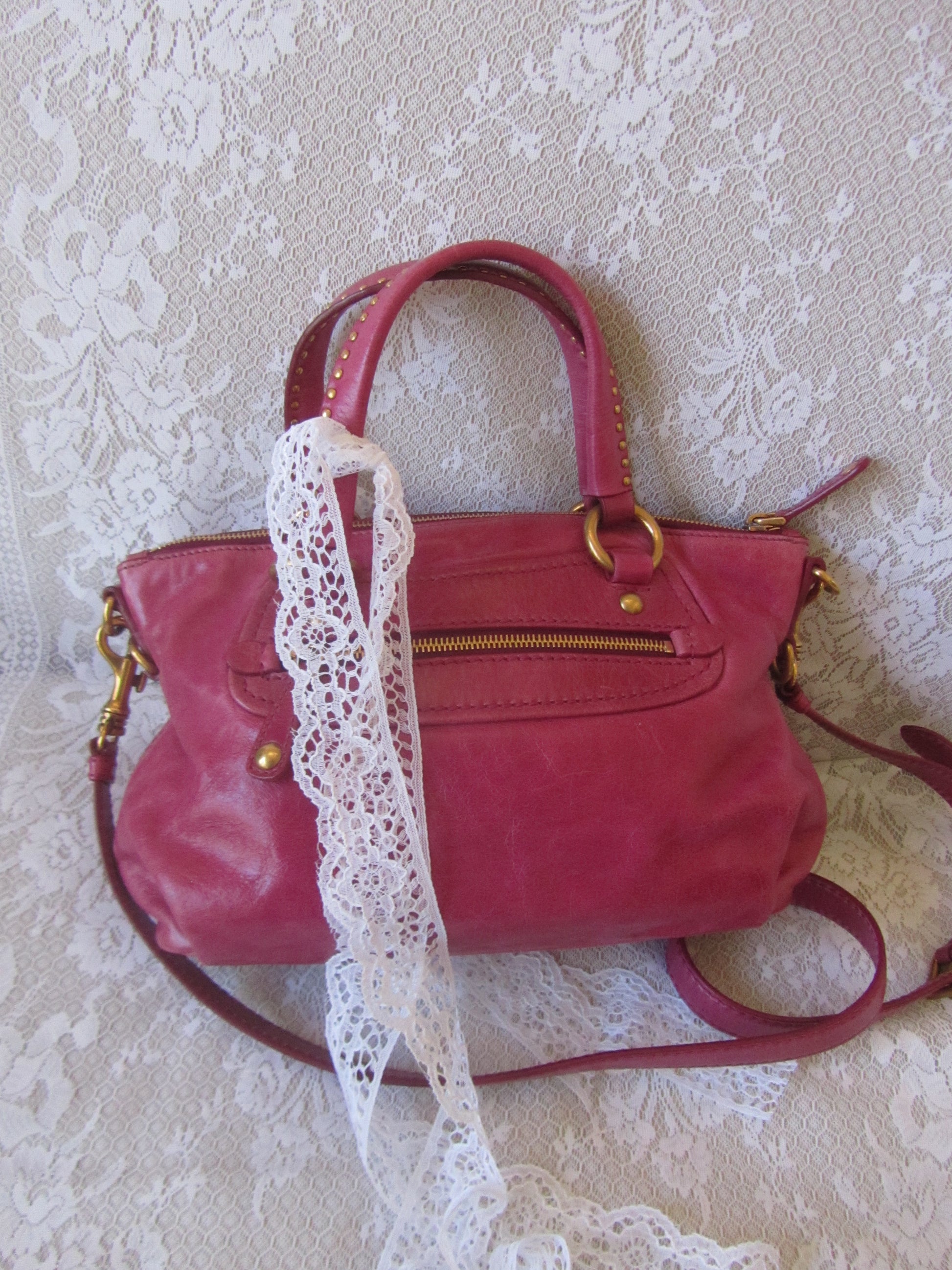 Red handbag with lace trim on a textured white background