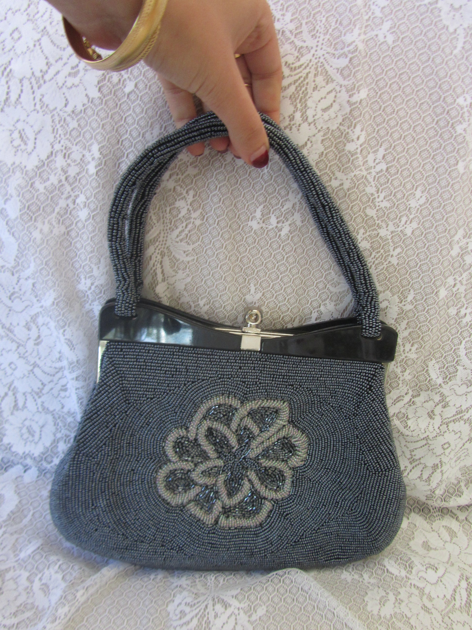 Gray beaded handbag with floral design on a textured surface