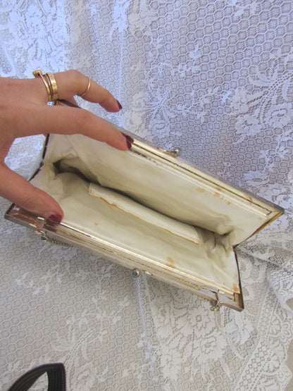Hand holding an empty beige clutch bag against a textured white background