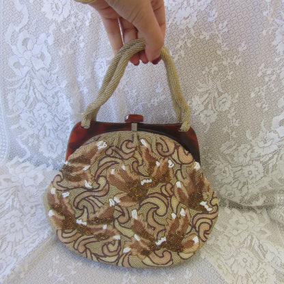 Hand holding a round, embroidered bag with intricate patterns on a textured white background